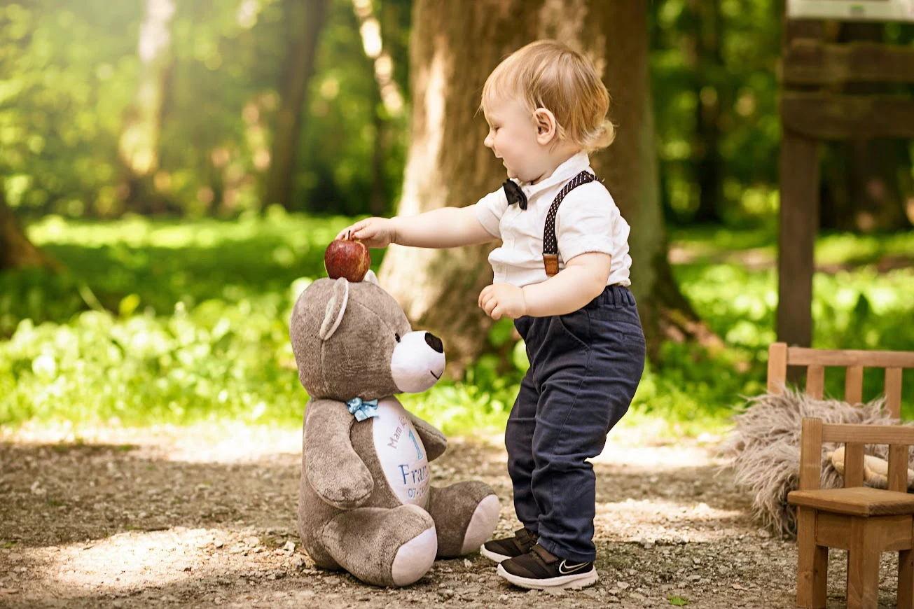 Chłopiec bawi się z personalizowanym misiem Lulukid w ogrodzie